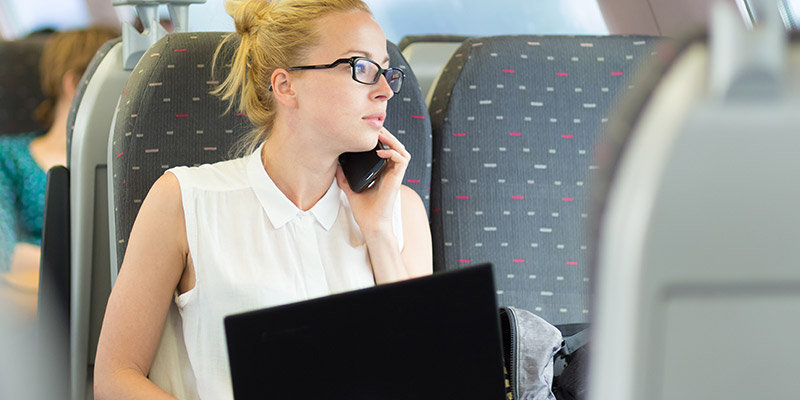 Eine Businessfrau sitzt in der Bahn und telefoniert - Telko